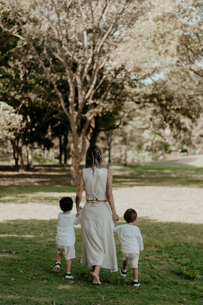 contact-img A mother and her two children stroll through a serene park setting.