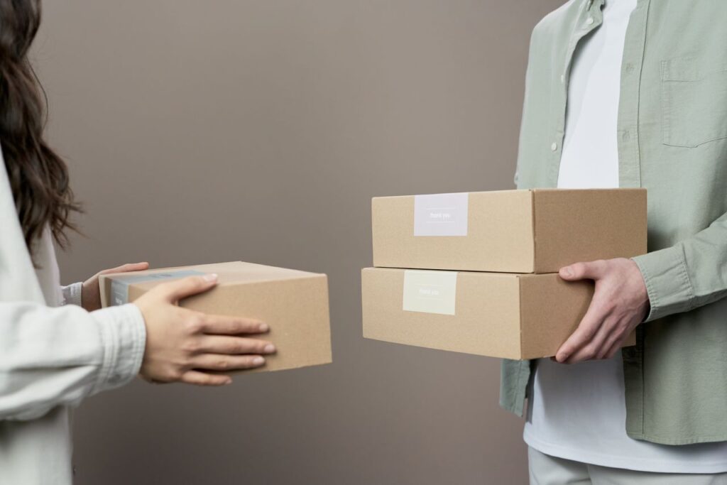 pexels-photo-9603486-9603486 Two people exchanging cardboard boxes indoors, emphasizing teamwork and logistics.
